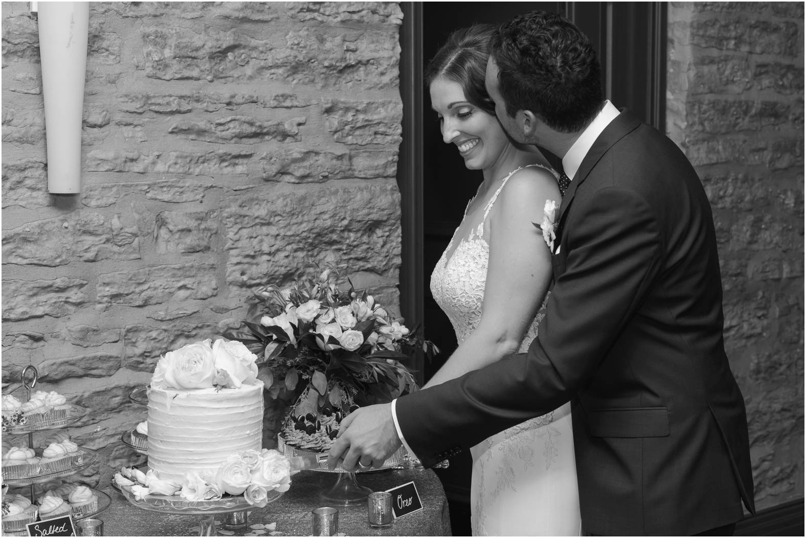 black and white image of bride and groom cutting their wedding cake