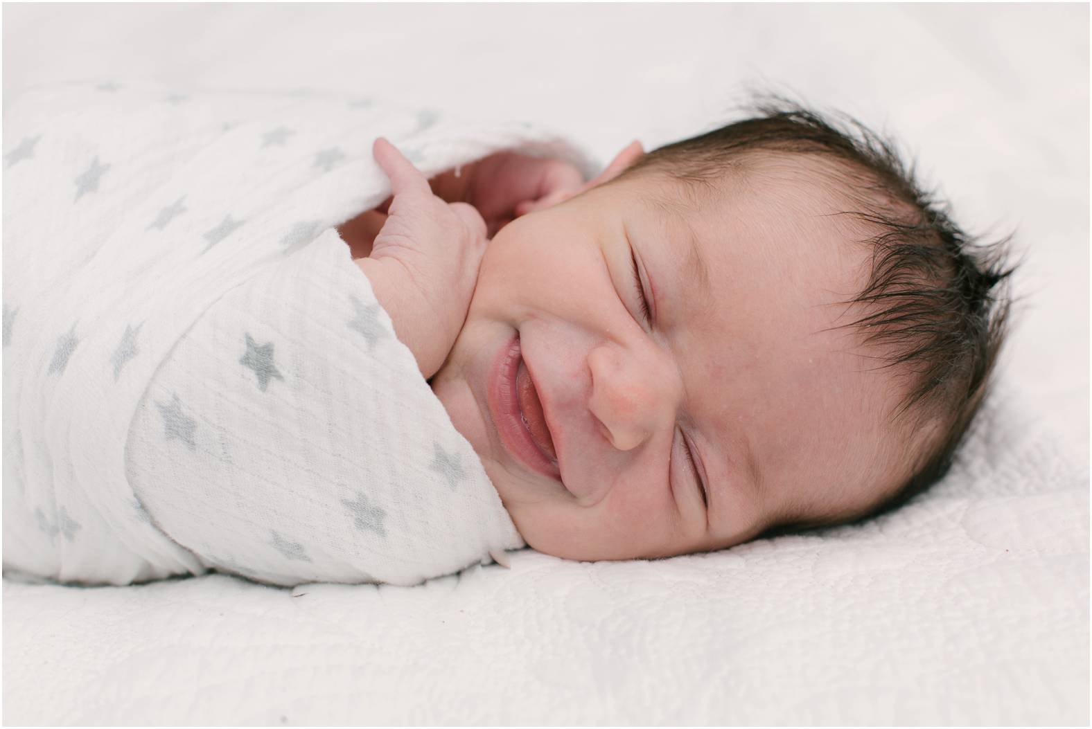 newborn baby boy swaddled and smiling
