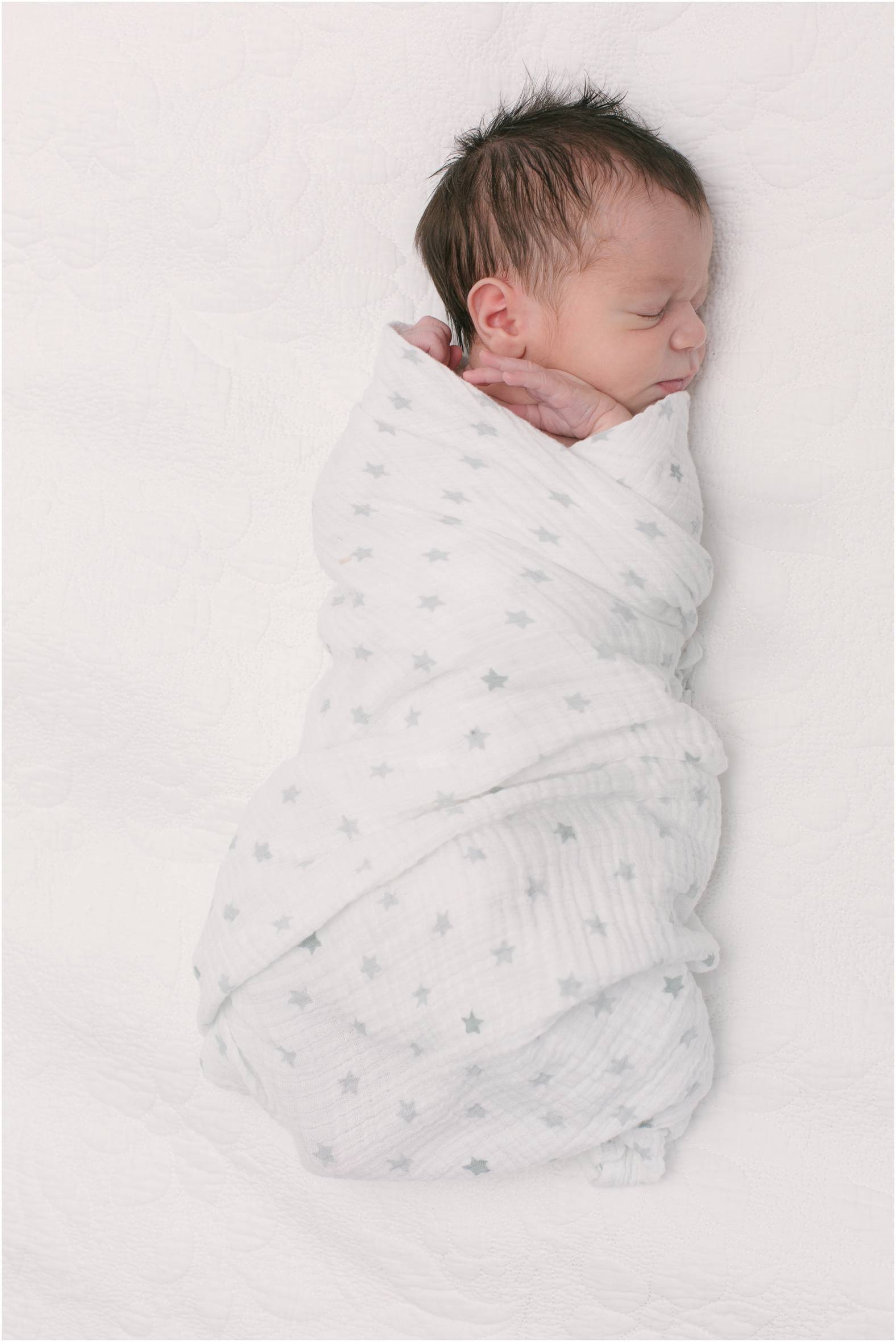 Newborn baby boy swaddled in neutral blanket
