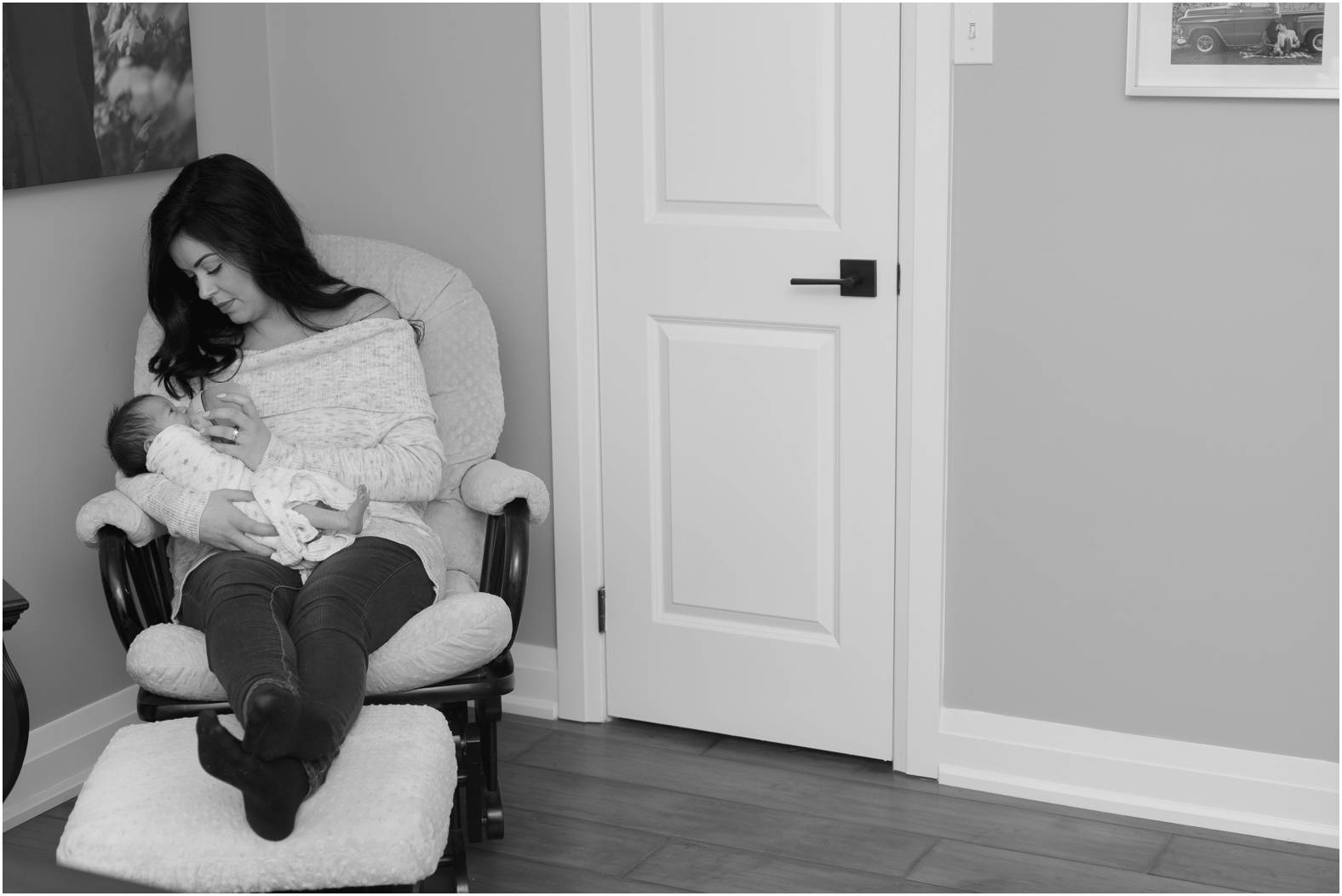 black and white image of mom feeding newborn baby on nursing chair